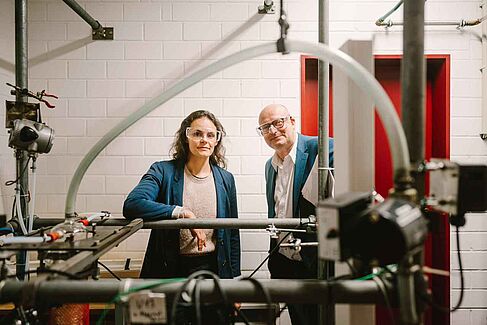 Markus Krämer und Silvia de Lima Vasconcelos schauen durch Rohre