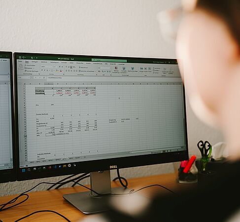 Detailaufnahme: Katrin Dziergwa schaut auf einem Monitor, auf dem Excel geöffnet ist