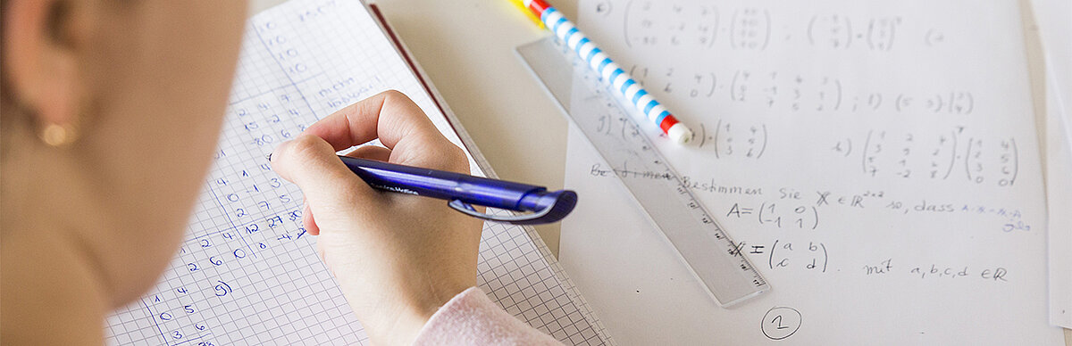 Studentin schreibt zahlen auf kariertes Papier