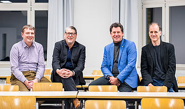 Vier Forscher sitzen auf einem Tisch