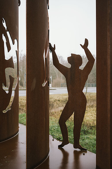 Stahlfiguren, die eine Stahlmauer überwinden und durchdringen