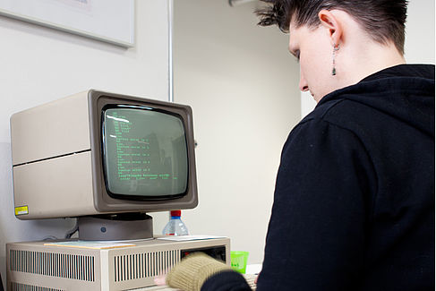 Eine Studentin sitzt vor einem alten Computer