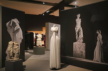 Ein Abendkleid von Madame Grès mit typischem Faltenwurf, daneben antike Skulpturen © HTW Berlin/Alexander Rentsch