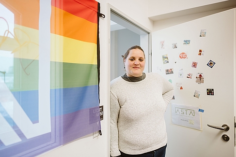 Kate Tomaschko neben einer Regenbogen-Flagge