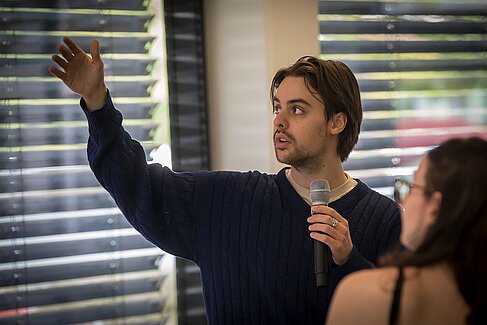 Robert Medicus zeigt auf die Präsentation an der Wand