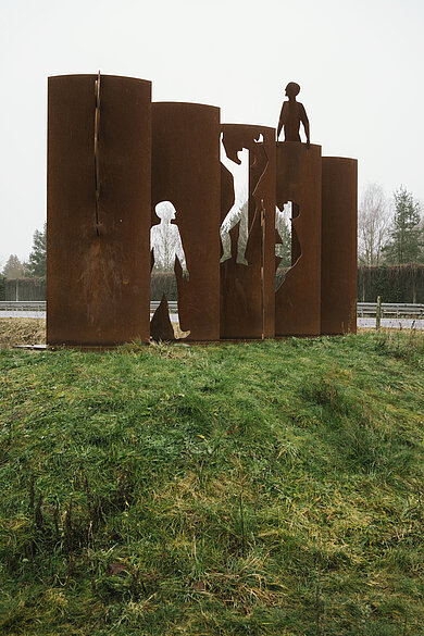 Stahlfiguren, die eine Stahlmauer überwinden und durchdringen