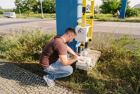 Projektmitarbeiter kniet an einem Sensorgehäuse.