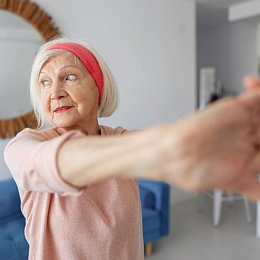 Eine ältere Frau strekckt beide Arme aus