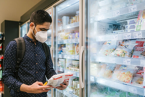 Majed Dandal mit einem Produkt vor dem Tiefkühlregal im Supermarkt