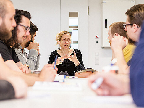 Professorin mit Studierenden am Tisch