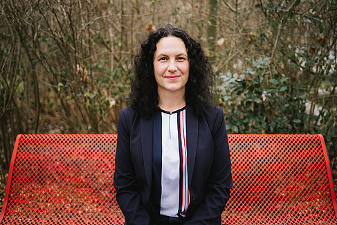 Dr Lena Simon auf einer roten Bank sitzend