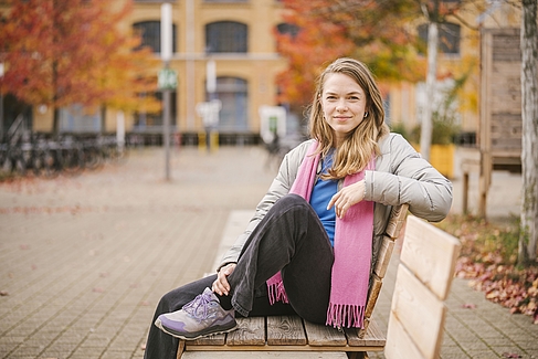 Mareike Lisker sitzt auf einer Bank auf dem Campus Wilhelminenhof