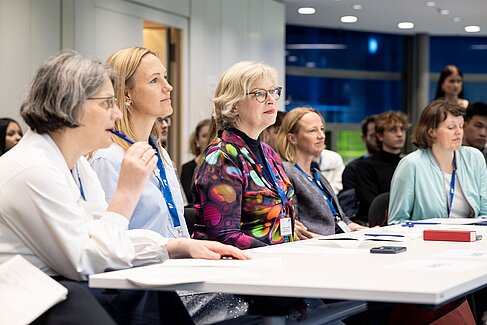 Mehrere Frauen sitzen aufmerksam an einem Tisch und machen Notizen