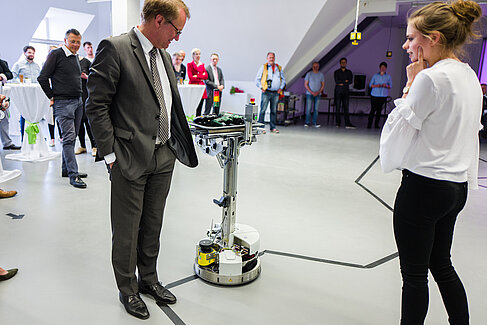 HTW-Präsident Klaus Semlinger testet die Fähigkeit des mobilen Roboters, Hindernisse zu erkennen. 