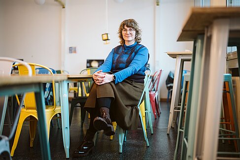 Daniela Hensel sitzt auf einem Stuhl in einem Seminarraum