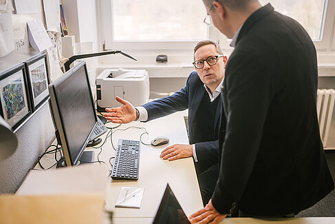 Two men look at a screen