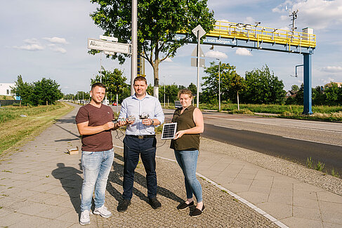 Drei Personen halten Sensoraufbauten und ein Solarmodul in der Hand.