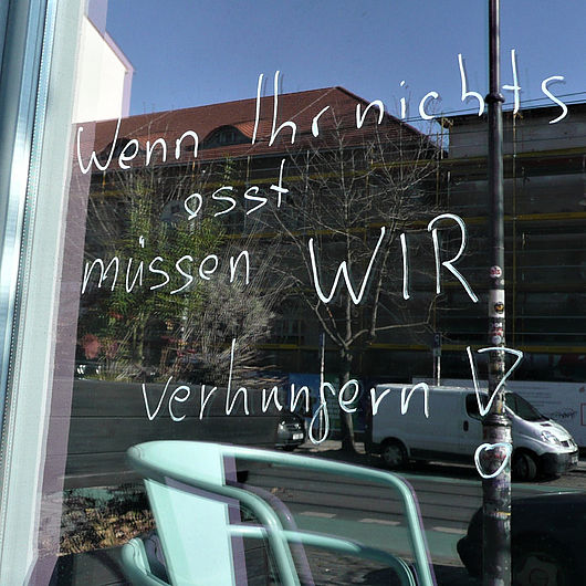 Schrift an einem Schaufenster: "Wenn ihr nichts esst, müssen wir verhungern!"
