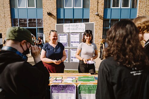 Zwei Mitarbeitende an einem Infostand zur Kampagne SpeakUp! bei der Erstsemesterbegrüßung