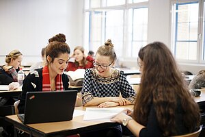 Professorin mit Studentinnen im Seminarraum 