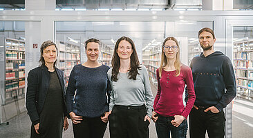 Fünf Menschen in einer Bibliothek