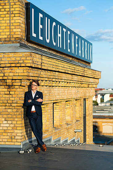 Stefan Otto neben dem Signet der Leuchtenfabrik