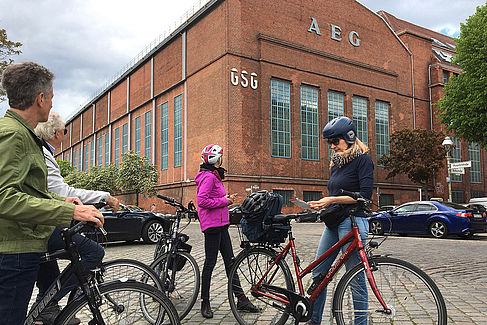 Radfahrer vor einem historischen Backsteingebäude der früheren AEG
