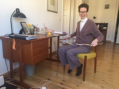 Eine Frau am Schreibtisch wendet sich der Kamera zu