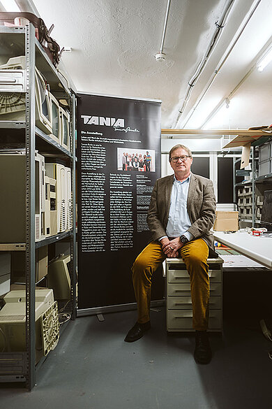 Oliver Rump sitzt auf einem Tisch im Archiv