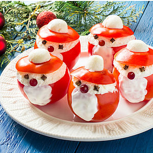 Mit Frischkäse gefüllte Tomaten, dekoriert wie Weihnachtsmänner