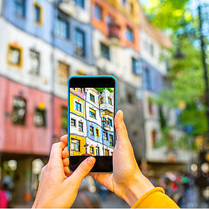 Jemand fotografiert die Fassade des Hundertwasserhauses in Wien mit dem Smartphone