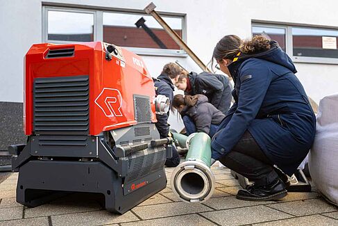 Menschen knien an einer Feuerlöschpumpe