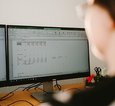 Detailaufnahme: Katrin Dziergwa schaut auf einem Monitor, auf dem Excel geöffnet ist