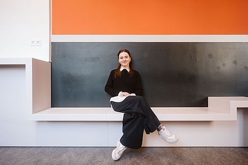 Sophie Brücklmeier sitzt auf einer Bank in Gebäude A, Campus Treskowallee