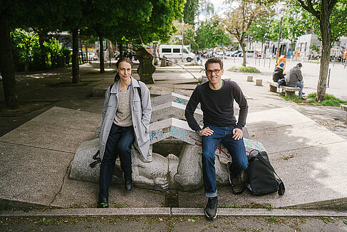 Nada Bretfeld (links) und Prof. Dr. Florian Koch sitzen auf einem Stein