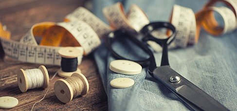 Nähutensilien wie Schere, Maßband, Knöpfe, Stoff und Nähgarn