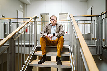 Oliver Rump sitzt auf einer Treppe