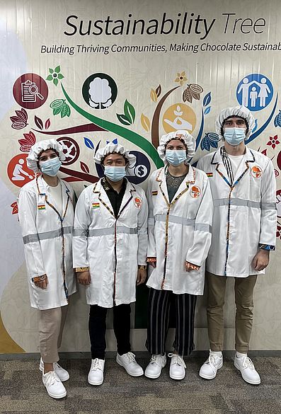 Die vier Studierenden mit Kitteln und Schutzmasken in der FairAfric Schokoladenfabrik © HTW Berlin/Bogdan Marchenko