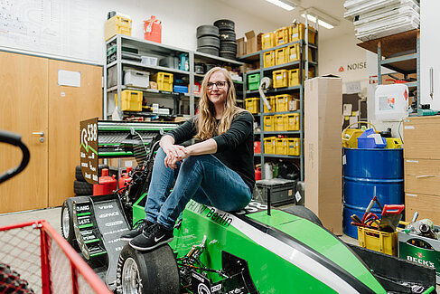 Susanne Nelke sitzt auf dem Rennwagen des HTW-Motorsport