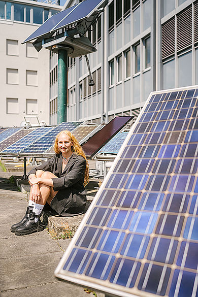 Frau sitzt neben einem Solarmodul