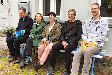 Fünf Menschen sitzen auf einer Bank