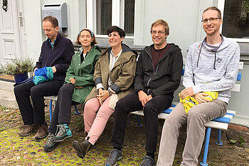 Fünf Menschen auf einer Bank sitzend