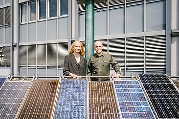 Frau und Mann hinter einem Solarmodul