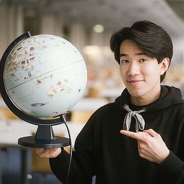 Student zeigt auf einen Globus © HTW Berlin/Alexander Rentsch